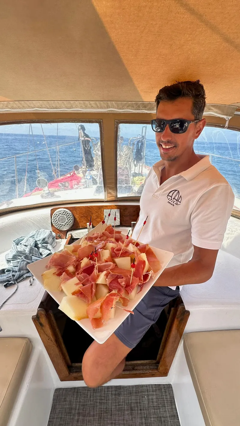 A member of the crew serving ham and melon on board