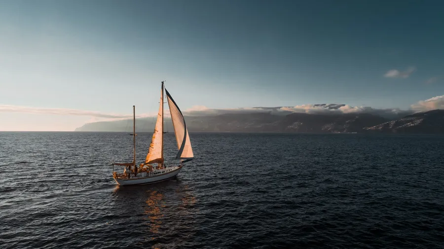 Spica sailing in the evening light, with the island behind