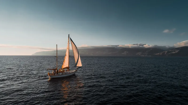 Spica sailing in the evening light, with the island behind